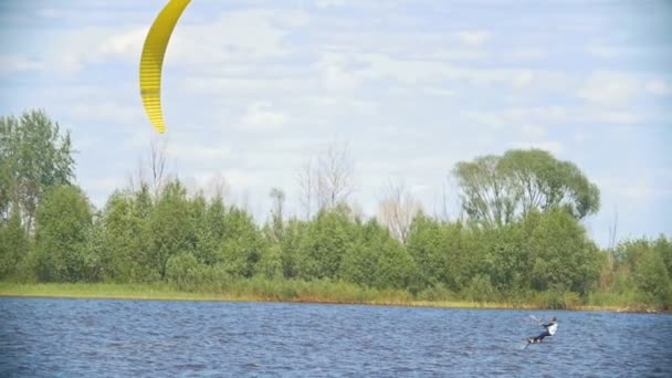 Kitesurfer bewegt sich auf dem Fluss auf dem Kiteboard mit Segel — Stockvideo