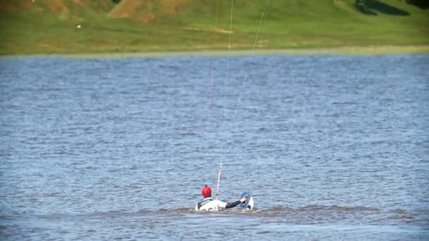 Kitesurfer dans l'eau sur voile et kiteboard dans sa main — Video