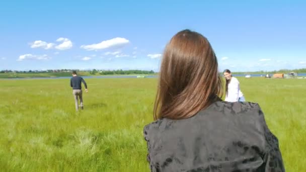 Молодые друзья играют во фрисби на летнем поле в солнечный день — стоковое видео