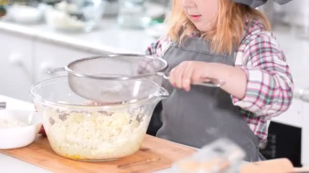 Маленькая девочка пекарь добавляет муку для теста для чизкейков — стоковое видео