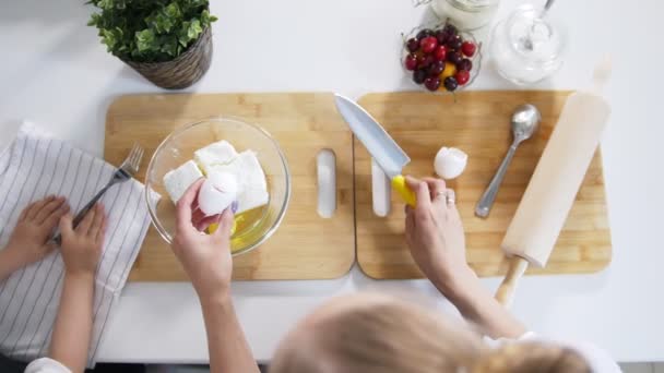 Mutter mit Tochter legt rohe Eier in den Teig für Quark-Pfannkuchen — Stockvideo