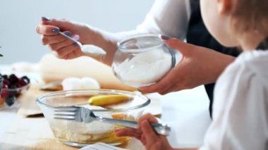 Kadın çocuğunu ile hamur krep hazırlamaya şeker koyar