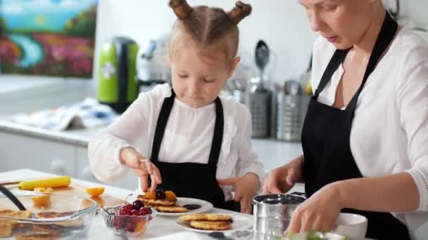 Mutter mit Tochter bestreut Pfannkuchen mit Puderzucker — Stockvideo