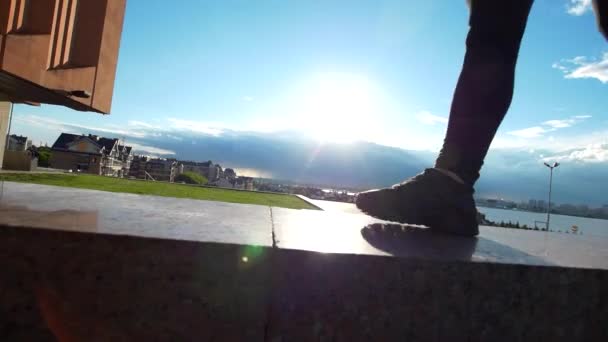 Deportiva piernas femeninas caminando en la acera a través de la puesta de sol de verano — Vídeos de Stock