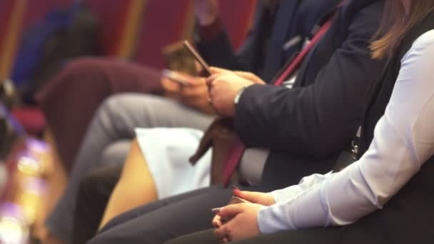 Люди, сидящие на бизнес-конференции, мужчина со смартфоном в руках — стоковое видео