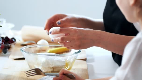 Женские руки разбивают яйцо в миске с ингредиентами для теста — стоковое видео