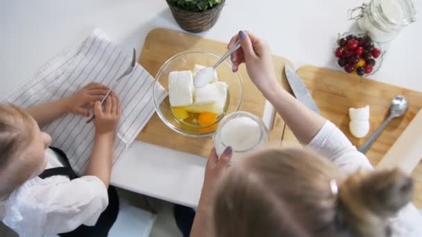 Äiti tyttärensä kanssa laittaa sokeria taikinaan raejuustopannukakkuja varten — kuvapankkivideo