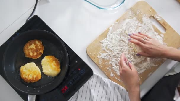 Las manos femeninas fritas en la sartén casera tortitas de queso cottage — Vídeo de stock