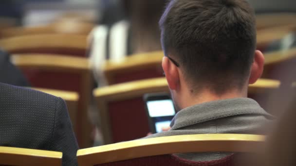 Вид сзади на молодого человека, сидящего на бизнес-конференции — стоковое видео