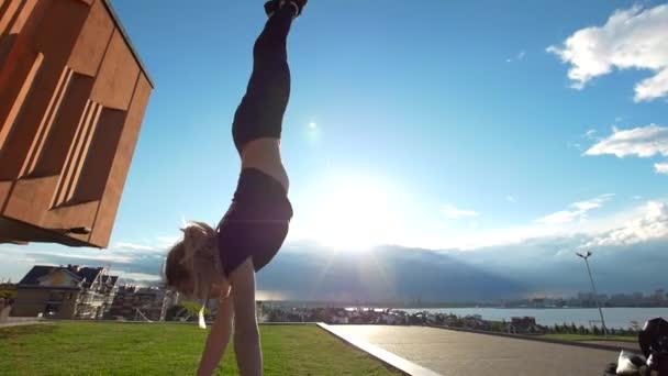 Ελκυστική νεαρή γυναίκα που περπατά handstand στο πεζοδρόμιο το καλοκαιρινό ηλιοβασίλεμα — Αρχείο Βίντεο