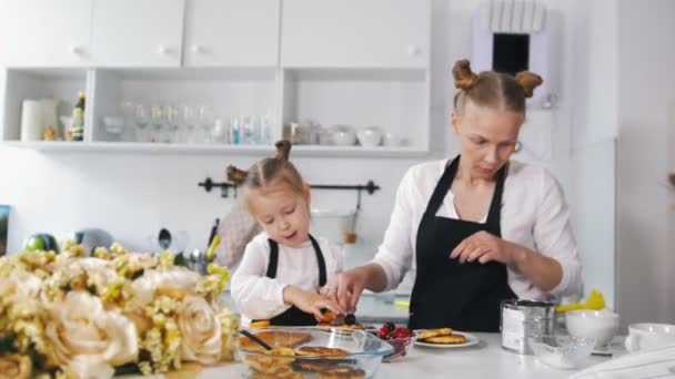 Mor och hennes lilla dotter på köket dekorerar dessert för frukost — Stockvideo