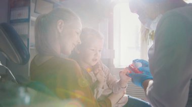 İncelenmesi ve annesi dizlerinin üzerinde oturan kızı danışmanlık diş hekimi