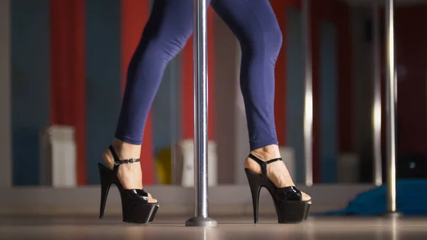 Pernas bonitas de mulher em sapatos pretos de salto alto dançando em um pólo em um estúdio — Fotografia de Stock
