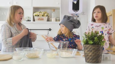 Anne önlük ve küçük kızlarla bir stüdyoda yemek için hazırlanıyor