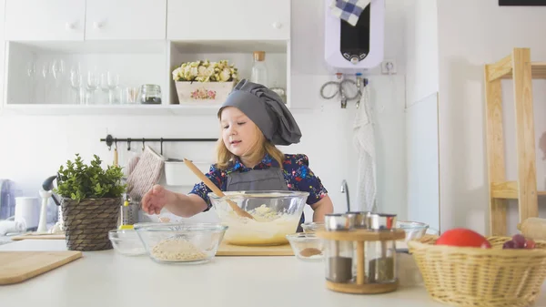 Милая маленькая девочка шеф-повар указал рукой на миски с ингредиентами для приготовления пищи — стоковое фото