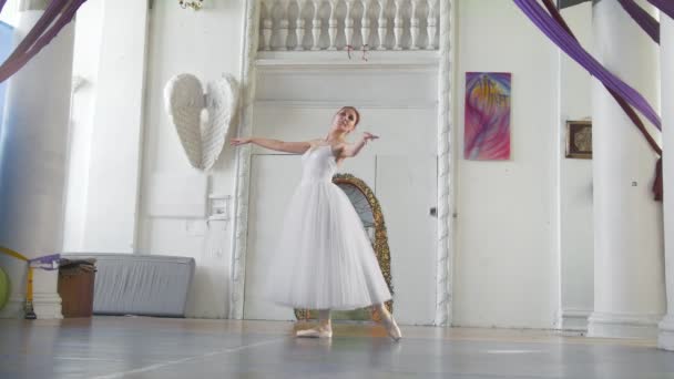 Jonge aantrekkelijke ballerina in een witte tutu poseren in ruime witte studio — Stockvideo