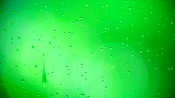 Green drops of water on the evening window - night lights through the glass — Stock Video