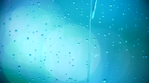 Blue drops of water on the evening window - night lights through the glass — Stock Video