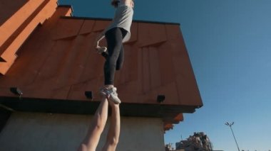 Genç adam kollarını Dengeleme kadın uçan çim holding yatan akrobatik öğeleri günbatımında gerçekleştirir.