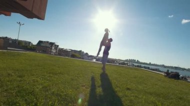 Genç çift açık kuş performans akrobasi pratik poz, kollarını günbatımında Dengeleme havada bir kadın genç adam atar