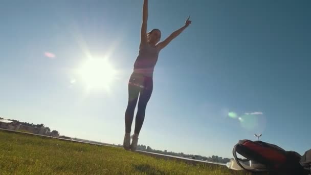 Joven gimnasta femenina realiza saltos sobre la hierba en un día soleado — Vídeos de Stock