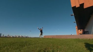 Genç kaslı adam akrobatik bir döndürür yeşil çimenlerin üzerinde günbatımında gerçekleştirir