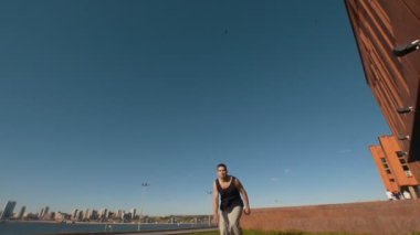 Beyaz genç adam akrobatik döndürür üzerinde arka plan cityscape güneşli gün gerçekleştirir