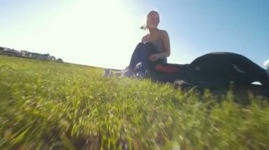 Genç adamla çimlerde oturan genç mutlu kadın ve spor ayakkabılarını güneşli bir günde değiştirir