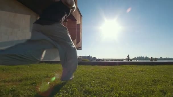 Mladý muž vede a provádí flip přes silnici na trávě — Stock video