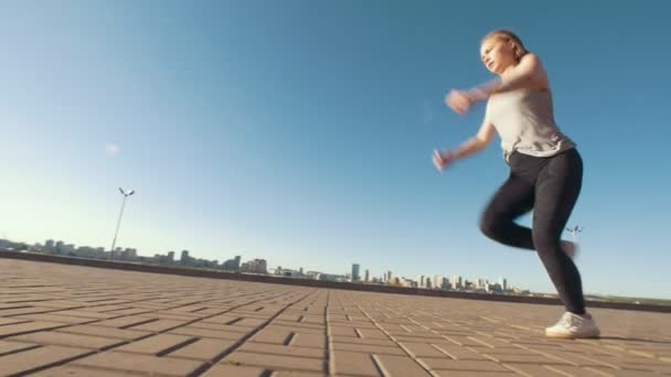 Jovem caucasiana realiza virada acrobática no asfalto em paisagem urbana de fundo — Vídeo de Stock