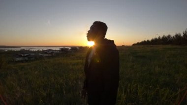 Genç Afro-Amerikan adam güzel günbatımında yaz çayır Sigara