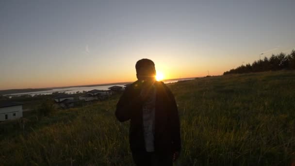 Mladý africký muž kouří v létě večer pole na krásný západ slunce — Stock video