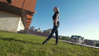 İnce genç kadın arka plan cityscape çimlere akrobatik atlama gerçekleştirir