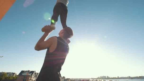 Ein paar junge Cheerleader üben an sonnigen Tagen im Freien - junger Mann hält Mädchen balancierend auf den Armen — Stockvideo