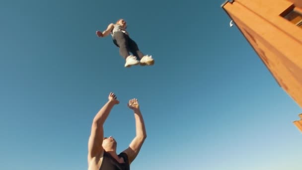 Par av unga cheerleaders öva utomhus på solig dag - ung man kastar flickan i luften — Stockvideo