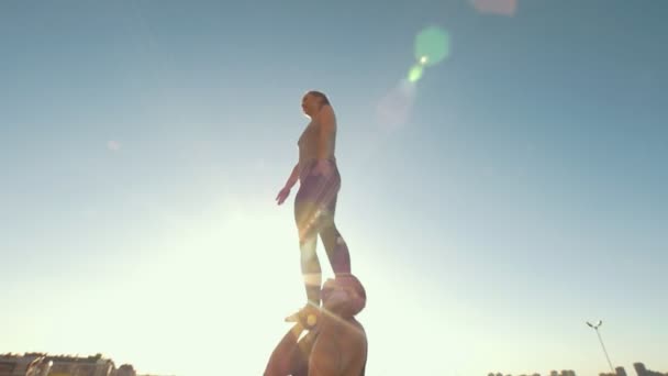 Команда болельщиц тренируется на открытом воздухе в летний день - мускулистый мужчина бросает девушку выполняя флип в воздухе — стоковое видео