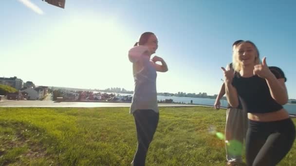 Tým mladých přátel roztleskávačky cvičení venku bavit, dívka ukazuje palec nahoru na letní den — Stock video