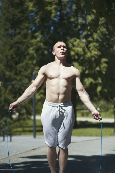 Bir ip, güneşli bir gün, açık havada egzersiz ile atlama atletik kaslı adam