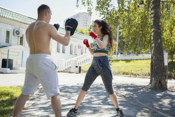 Joven musculoso hombre y mujer dedicado al boxeo en el parque ar día soleado —  Fotos de Stock