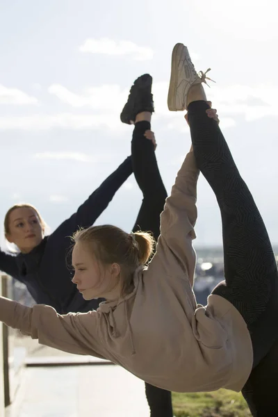 Duas jovens mulheres atraentes fazendo acrobacias com paisagem urbana em segundo plano — Fotografia de Stock