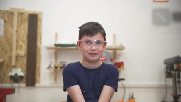 Adolescent drôle garçon jette de la sciure de bois dans l'air dans l'atelier de menuiserie — Video