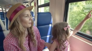 Mutlu anne ve kızı seyahat birlikte - trende gider ve pencereden dışarı bakmak