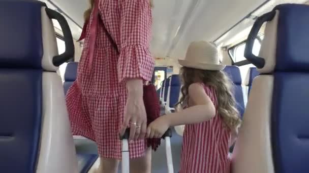 Rear view of mother and little daughter in same dresses walks in empty train car — Stock Video