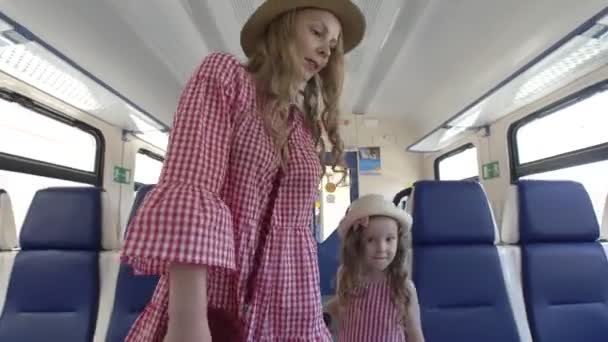 Attraktive junge Frau und ihre kleine Tochter laufen in leerem Eisenbahnwaggon — Stockvideo