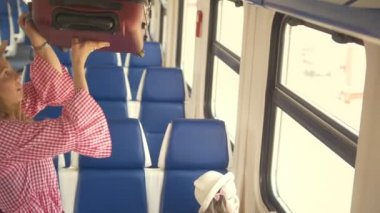 Genç çekici anne kızıyla hızlı tren - seyahat edecek koyar çantayı en üst rafta