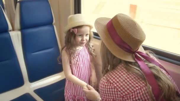 Linda niña viajando junto con su madre - tomados de la mano y hablando en tren cerca de la ventana — Vídeos de Stock