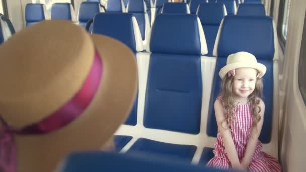 Χαριτωμένο μικρό κορίτσι, που ταξιδεύουν σε άδειο τρένο με τη μαμά - στέλνει ένα φιλί αέρα — Αρχείο Βίντεο