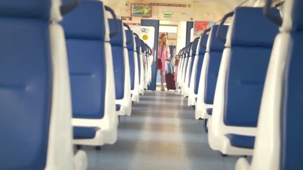 Alegre niña con su mamá entra en el vagón de tren vacío — Vídeo de stock