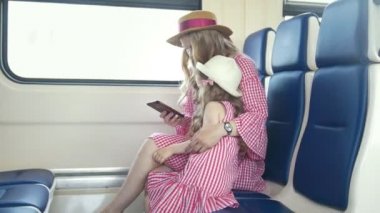 Tren ve cep telefonuyla Genç beyaz anne ve kızı silah binmek