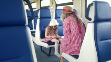 Küçük kız trende bir smartphone ve annesi oturan kullanın